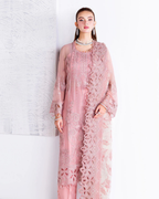 Woman wearing a pink lace outfit against a white brick wall.