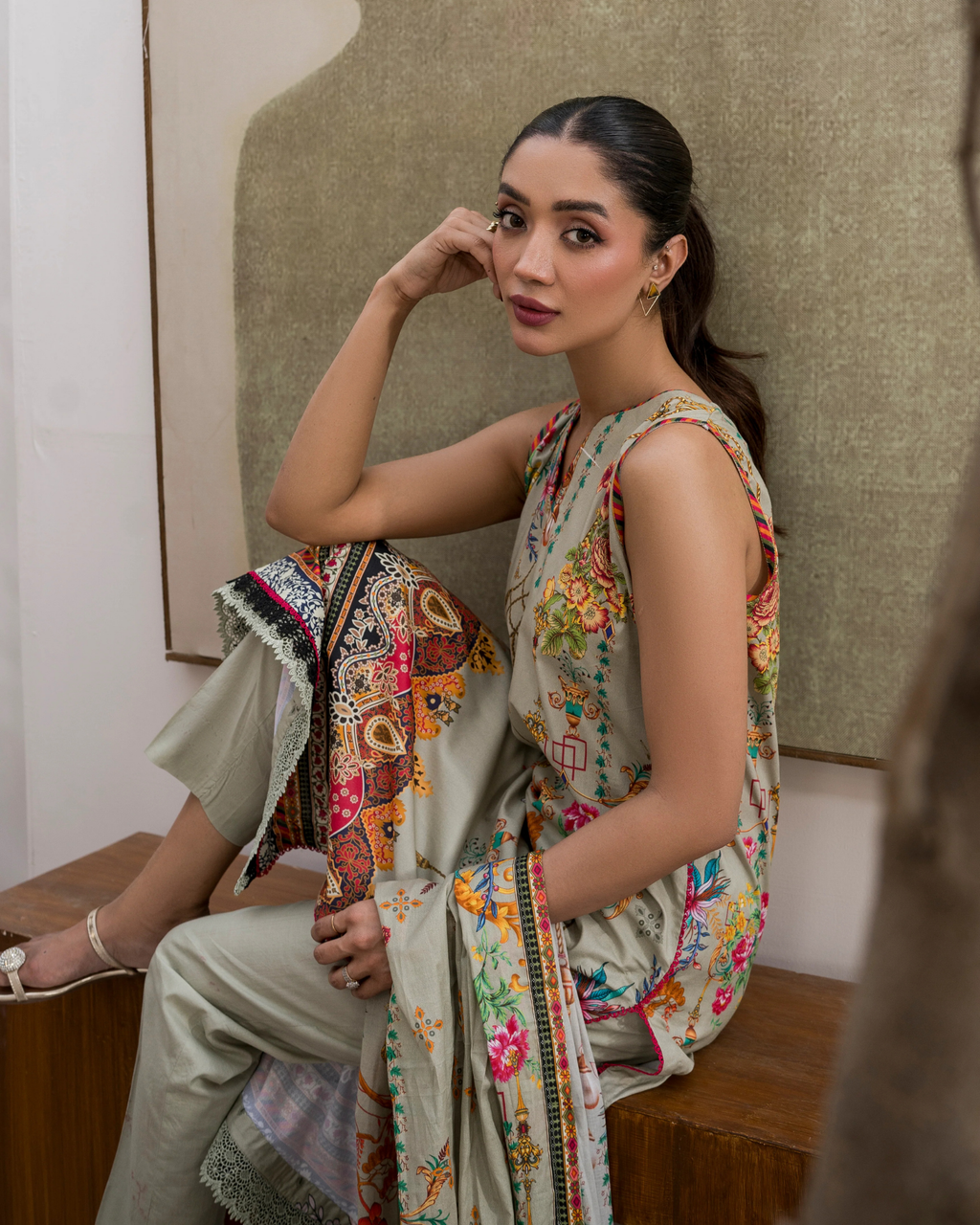 Woman in a colorful dress sitting on a wooden bench with a textured wall background