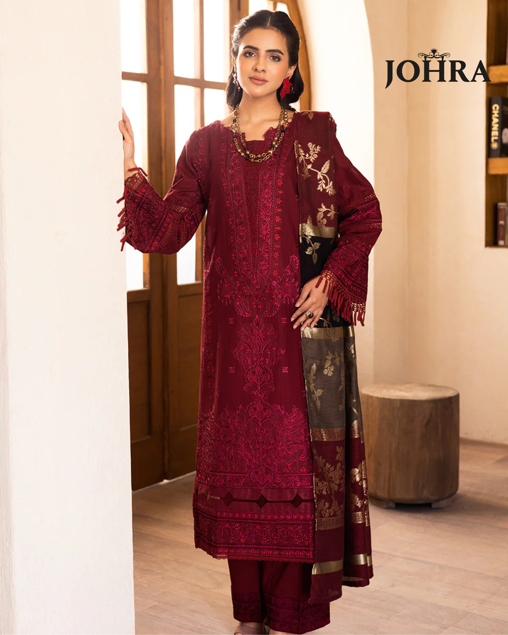 Woman wearing a maroon embroidered traditional outfit with JOHRA branding.