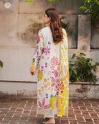 Woman wearing a floral dress with a yellow dupatta in an outdoor setting.