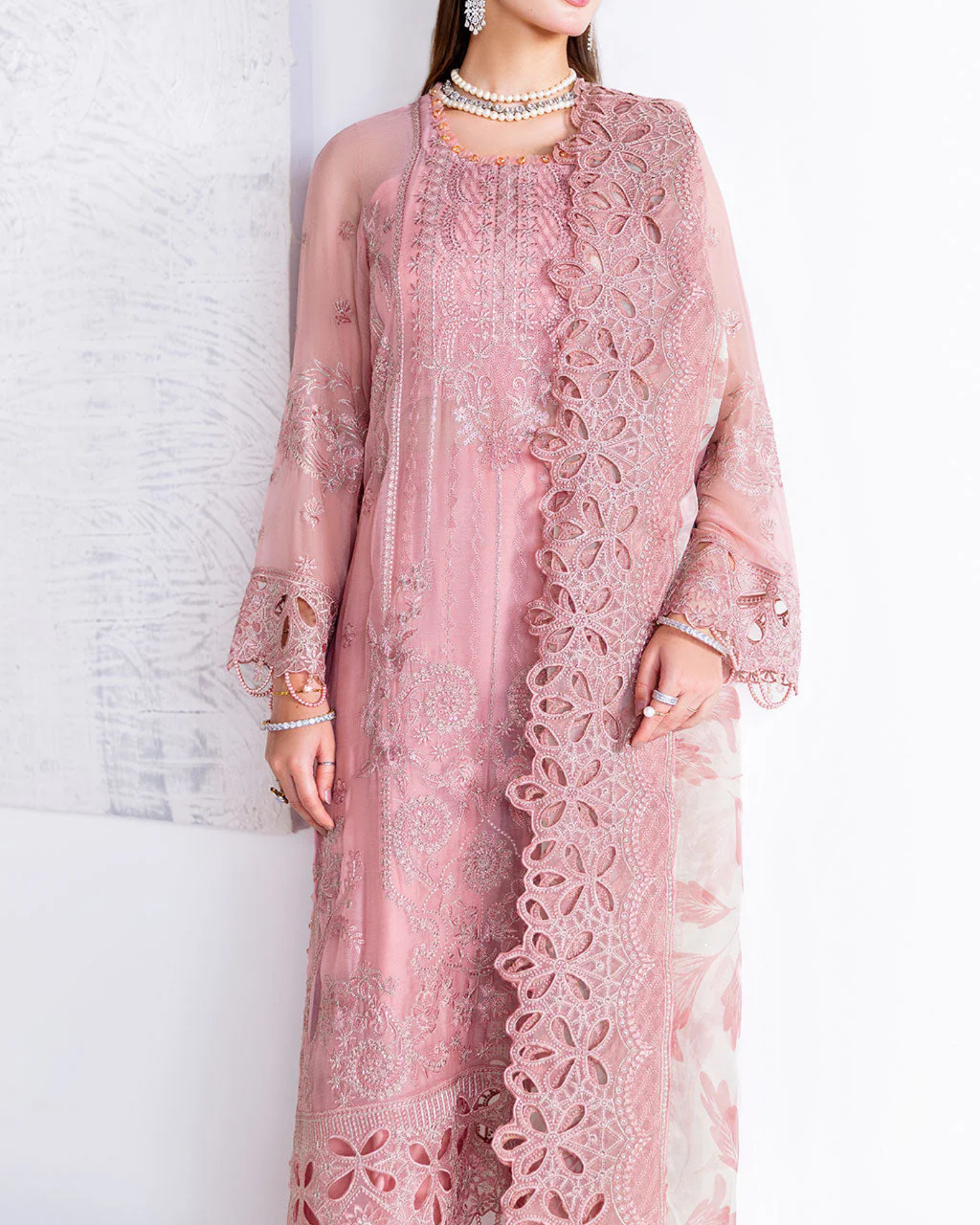 Pink lace dress worn by a person against a white background