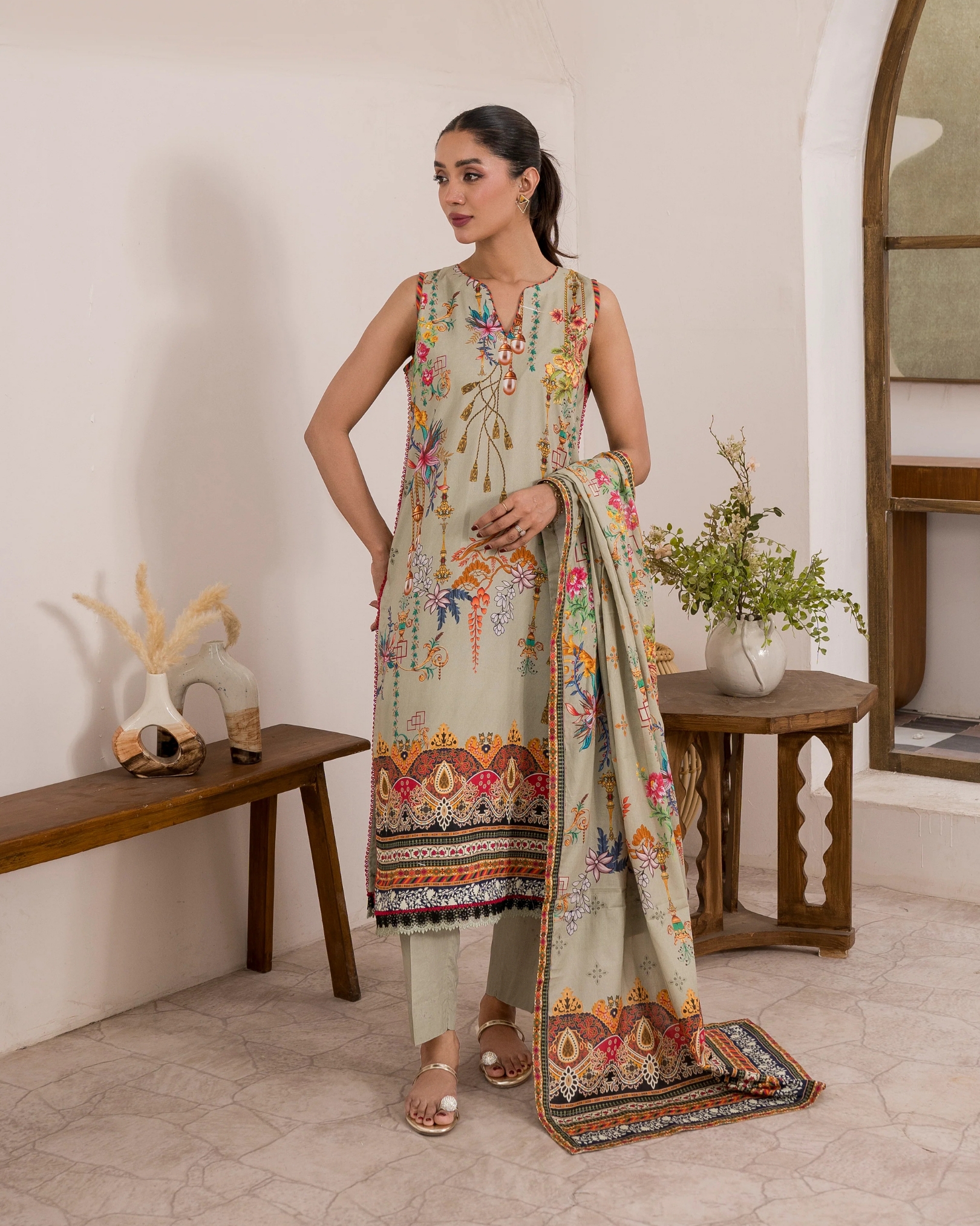 Woman wearing a floral dress with a matching dupatta in a room setting.