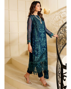 Woman in a dark blue embroidered dress standing on a staircase.