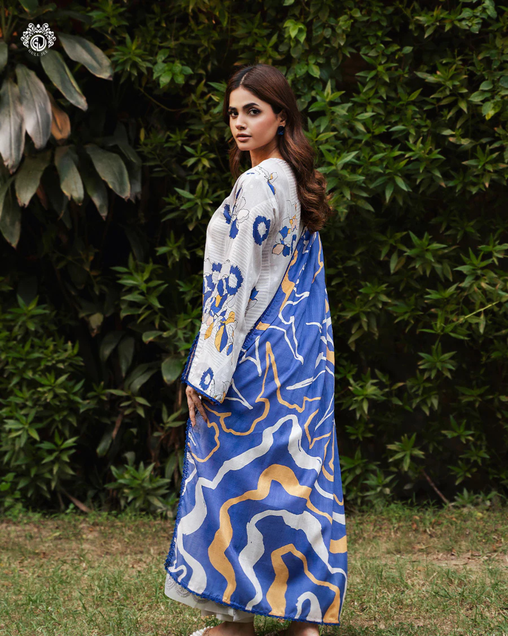 Woman wearing a blue and white patterned dress with a white cardigan in an outdoor setting.