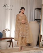 Woman in a beige embroidered outfit standing in a room with decor elements.