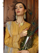 Woman in a yellow embroidered outfit holding a vase with peacock feathers indoors.