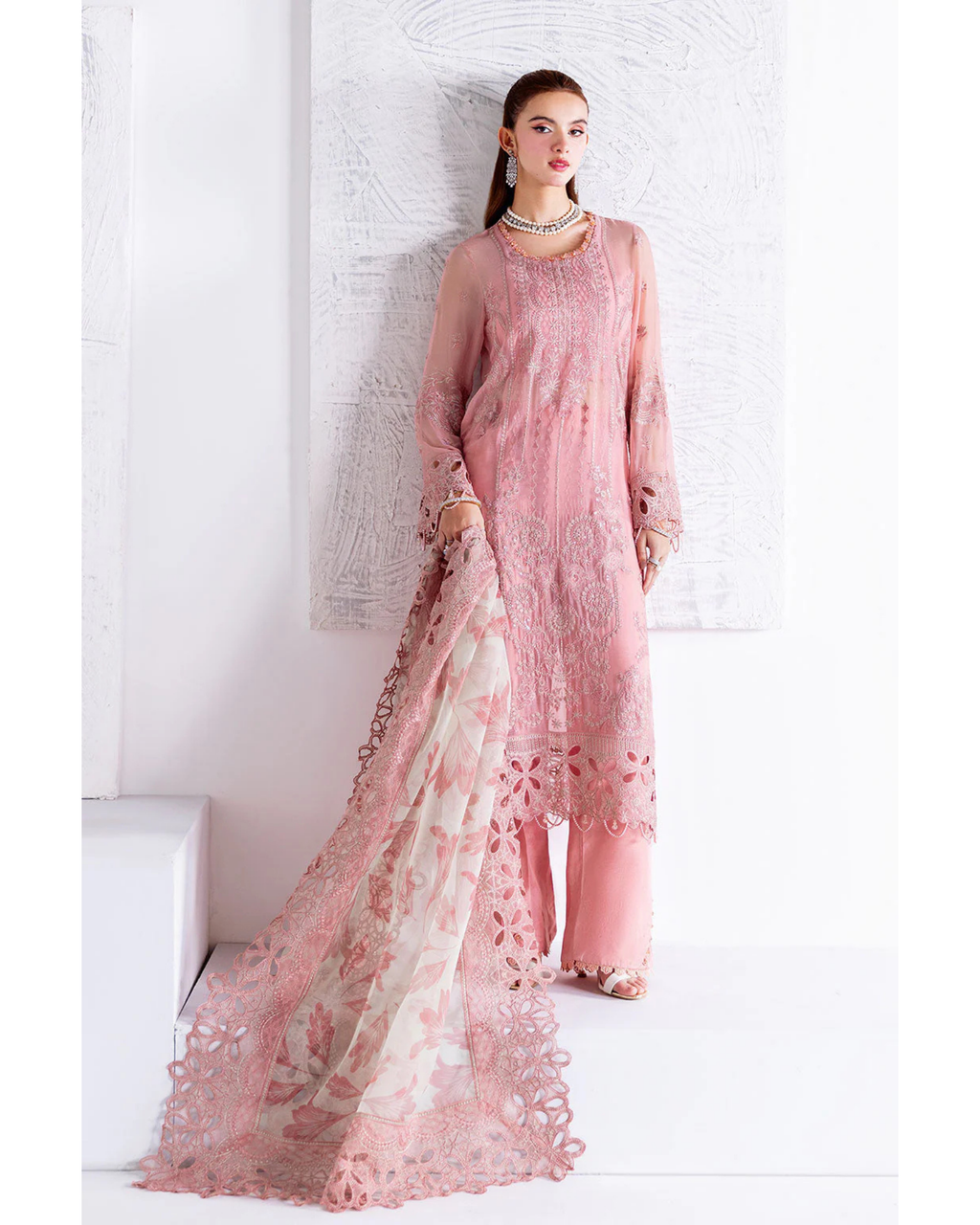 Woman wearing a pink lace outfit against a white background