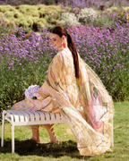 Woman in a floral dress sitting on a bench in a field of flowers