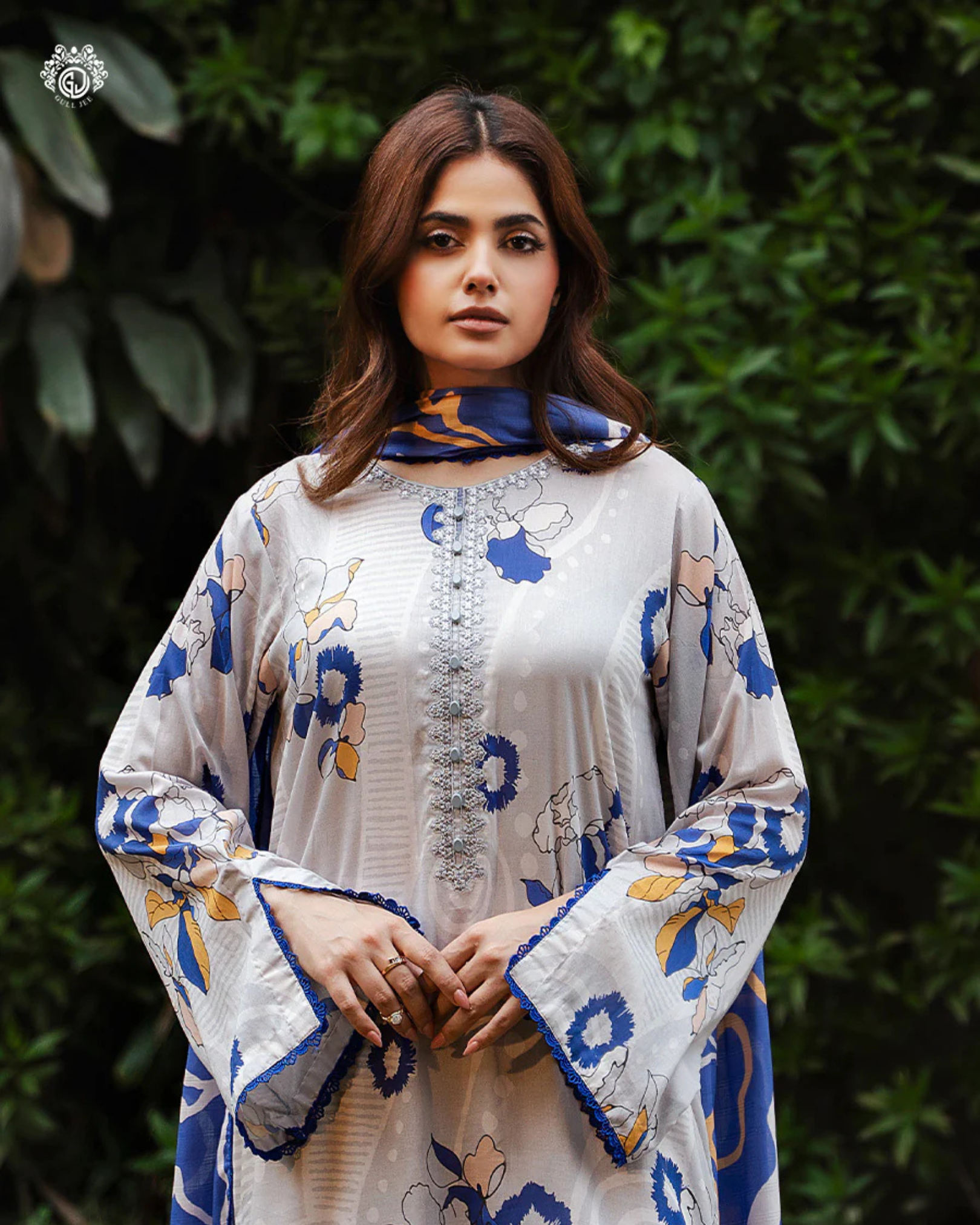Woman wearing a floral-patterned outfit with a green leafy background