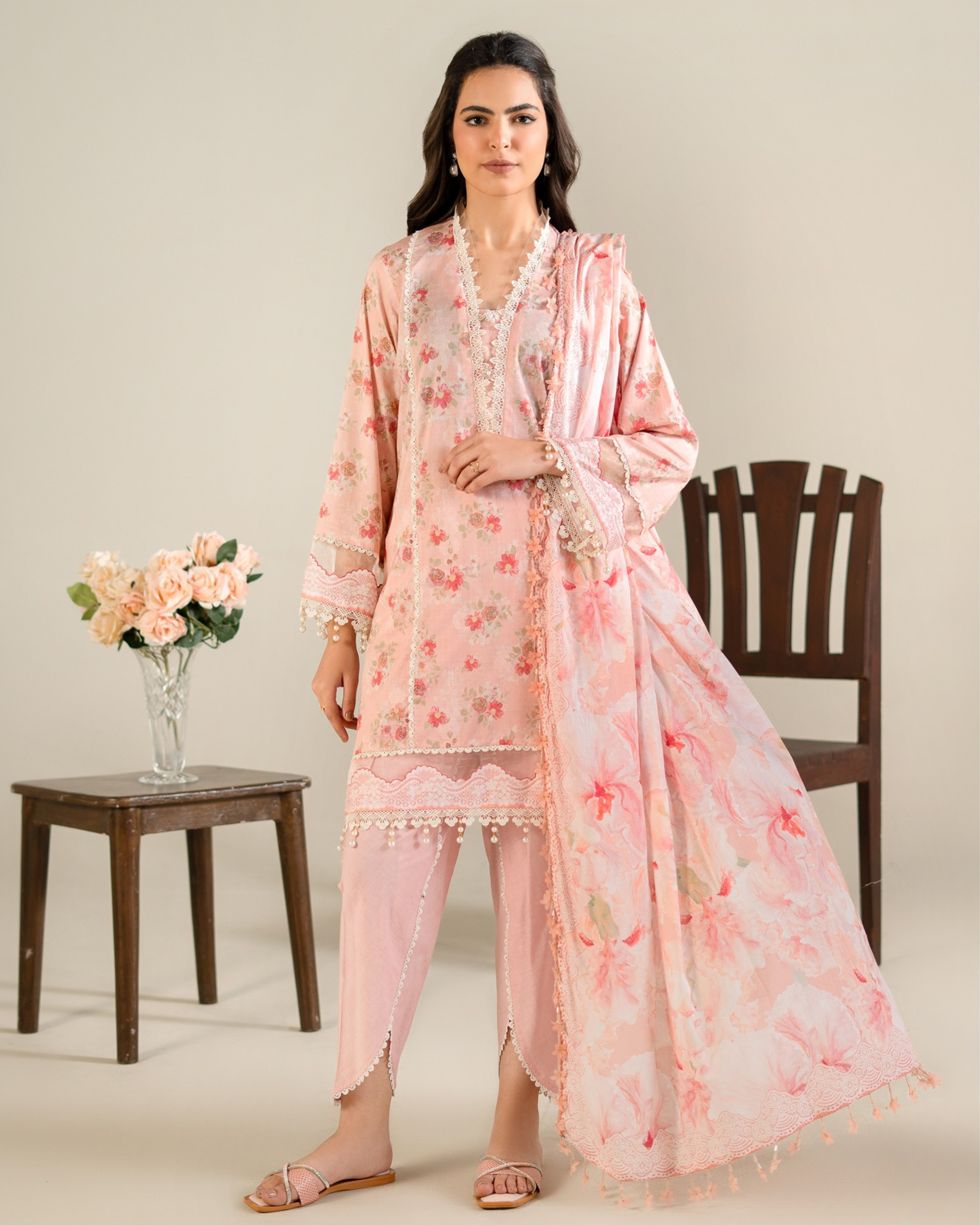 Woman wearing a pink floral outfit with a chair and flowers in the background
