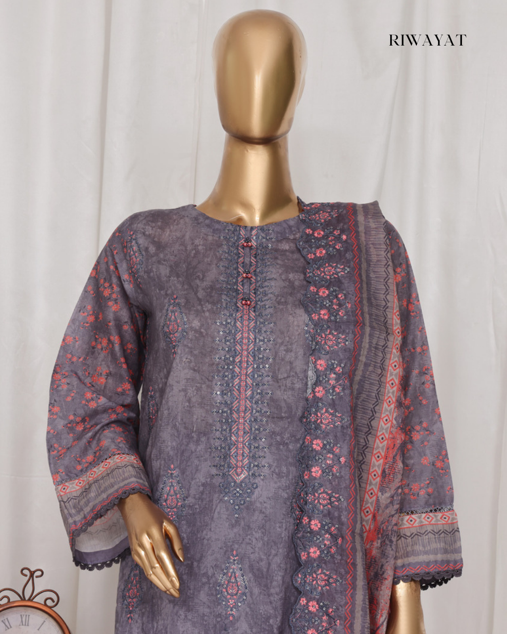 Mannequin wearing a purple embroidered outfit with a matching shawl against a white background, branded 'RIWAYAT'.