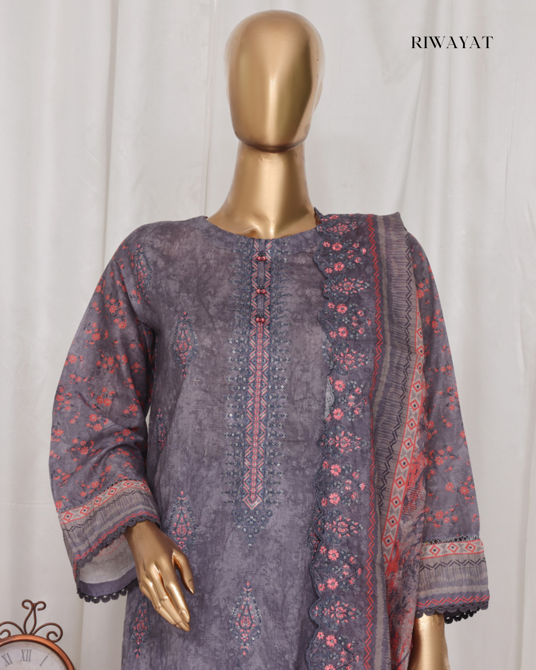 Mannequin wearing a purple embroidered outfit with a matching shawl against a white background, branded 'RIWAYAT'.
