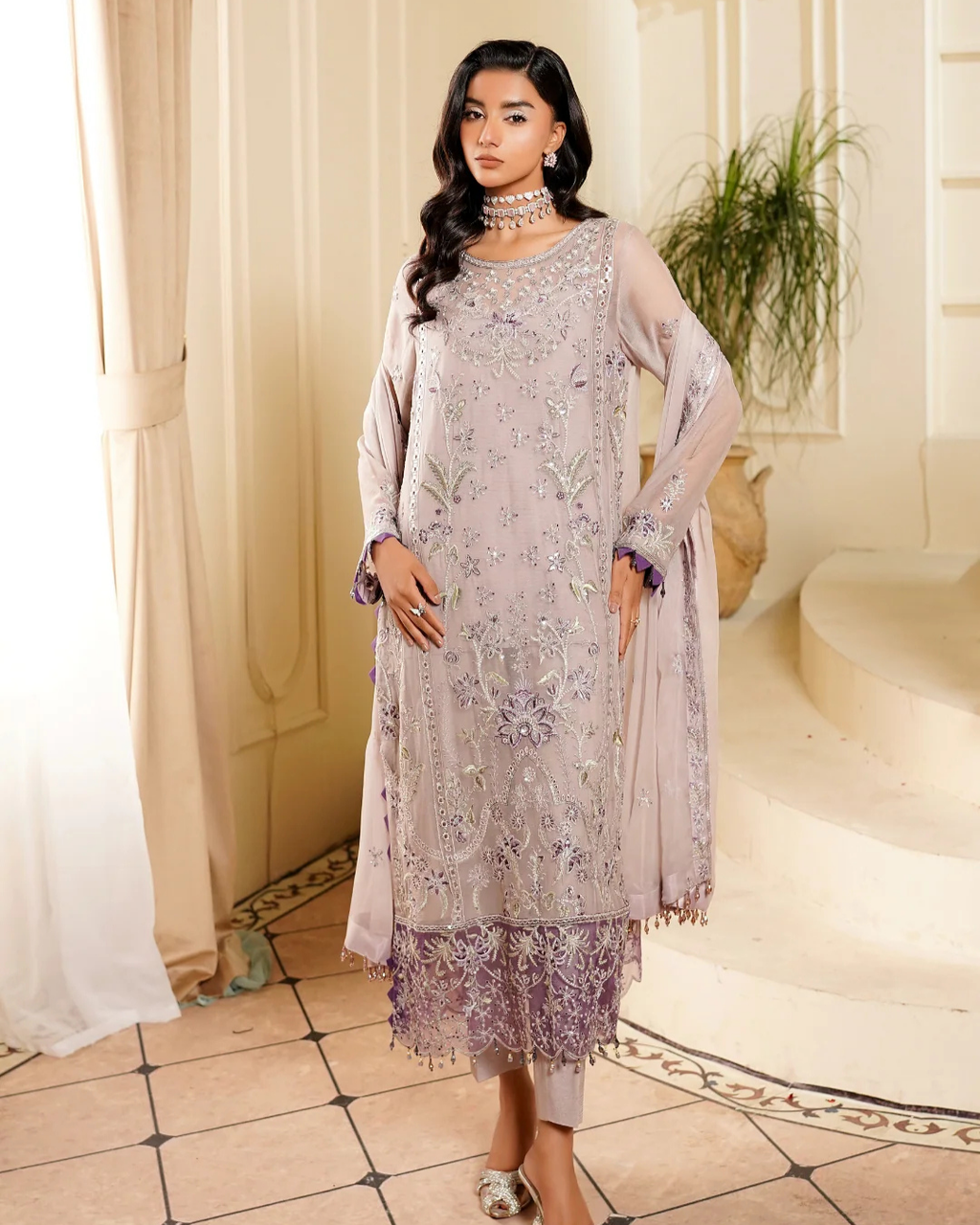 Woman wearing a light purple embroidered dress with a matching dupatta in an elegant indoor setting.
