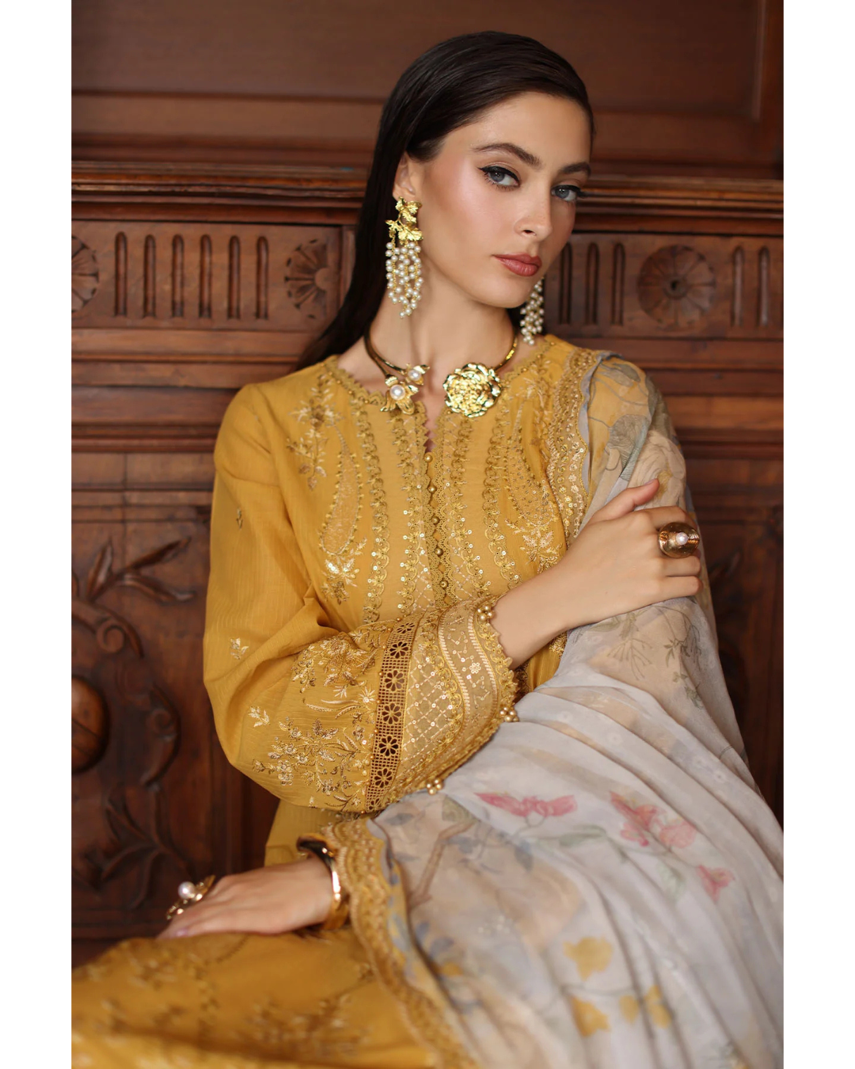 Woman in a yellow embroidered outfit with a wooden panel background