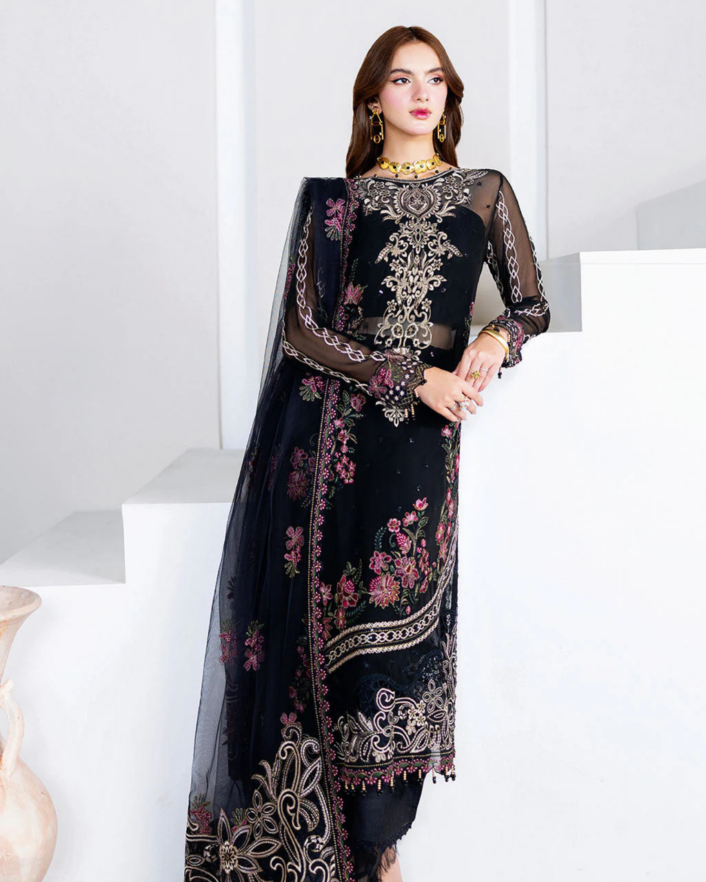 Woman wearing a black embroidered traditional outfit with a white background