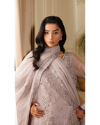 Woman wearing a light pink embroidered outfit with a matching dupatta indoors.