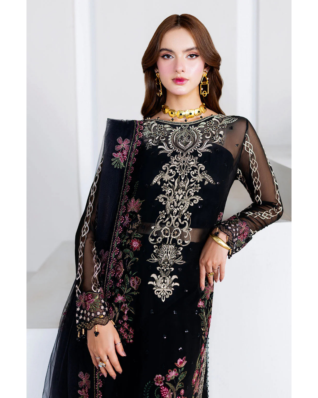 Woman wearing a black embroidered outfit with a white background