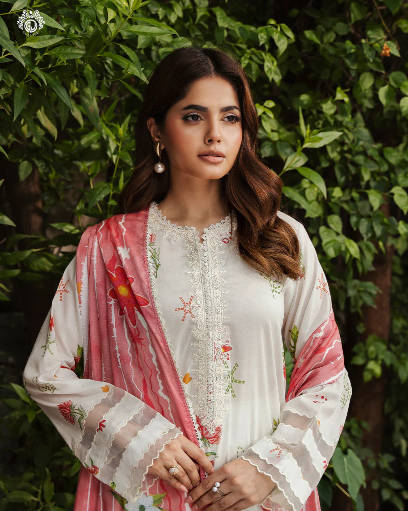 Woman wearing a white and pink embroidered outfit with a green leafy background