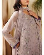 Woman wearing a lavender embroidered outfit with a matching dupatta indoors.