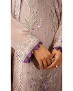 Close-up of a hand wearing a ring on a garment with floral embroidery.