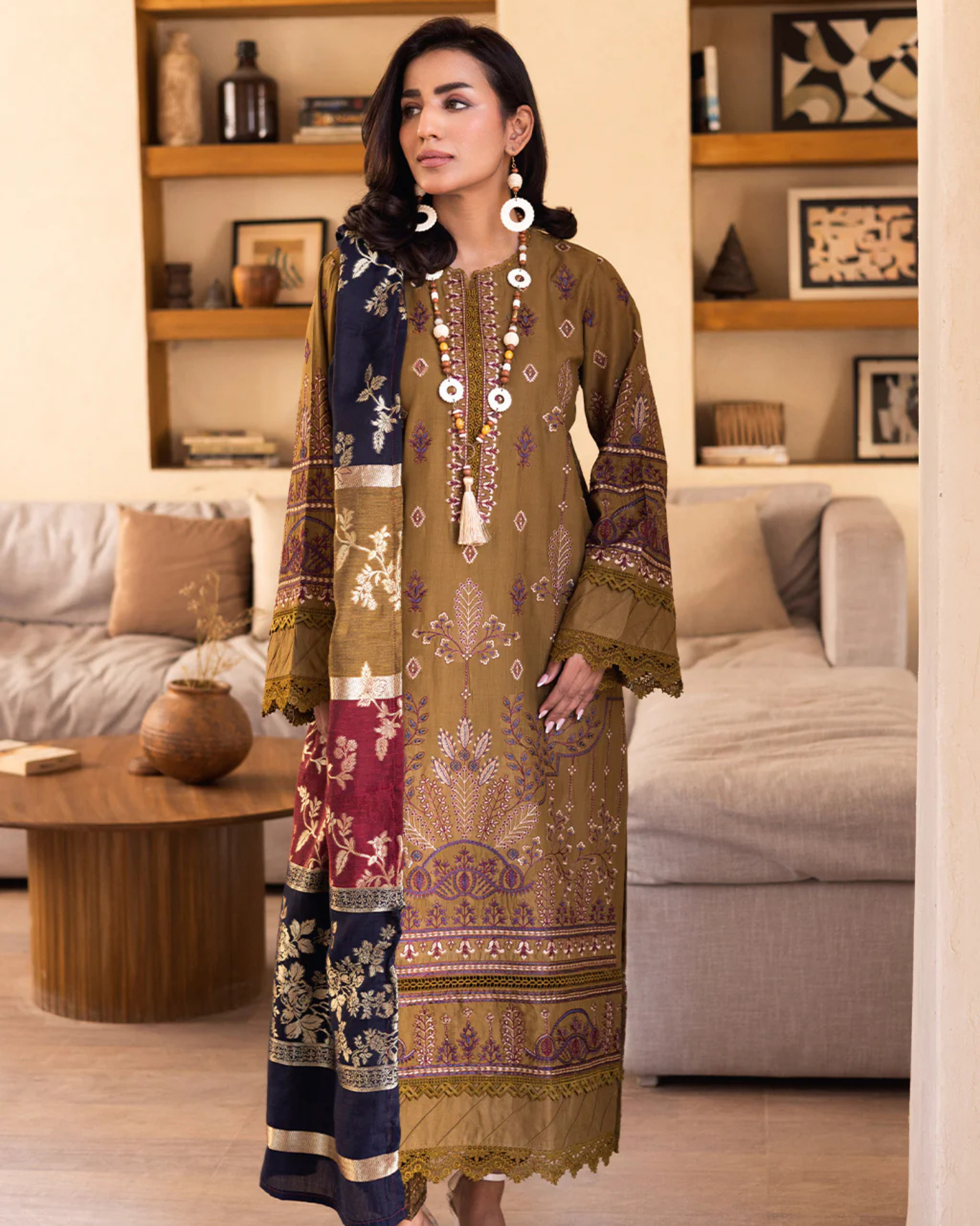 Woman in a traditional embroidered outfit standing in a living room.