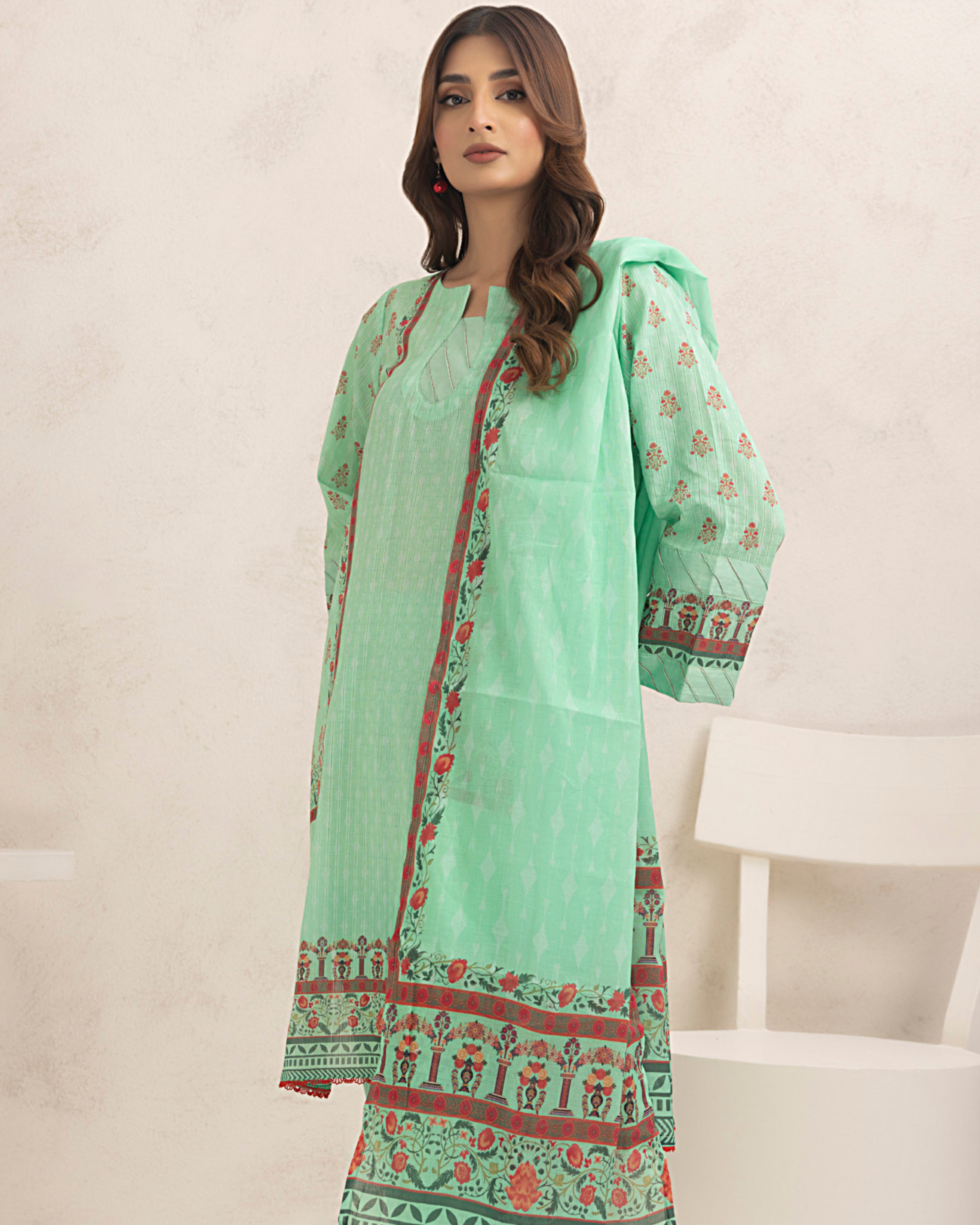 Woman wearing a light green traditional outfit with floral patterns on a neutral background