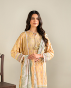 Woman wearing a yellow embroidered outfit with a matching shawl against a beige background