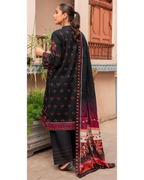 Woman wearing a black embroidered outfit with a colorful dupatta, standing outdoors.