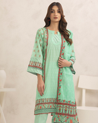 Woman wearing a light green embroidered traditional outfit with a plain background