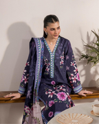 Woman wearing a floral kimono-style outfit sitting on a wooden bench.