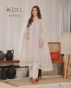 Woman in a white embroidered outfit standing in a room with decor elements.