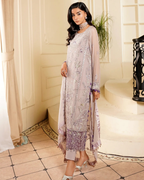 Woman in a light purple embroidered outfit standing in a decorative interior setting.