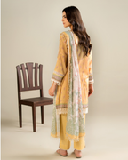 Woman wearing a yellow and green traditional outfit with a chair in the background