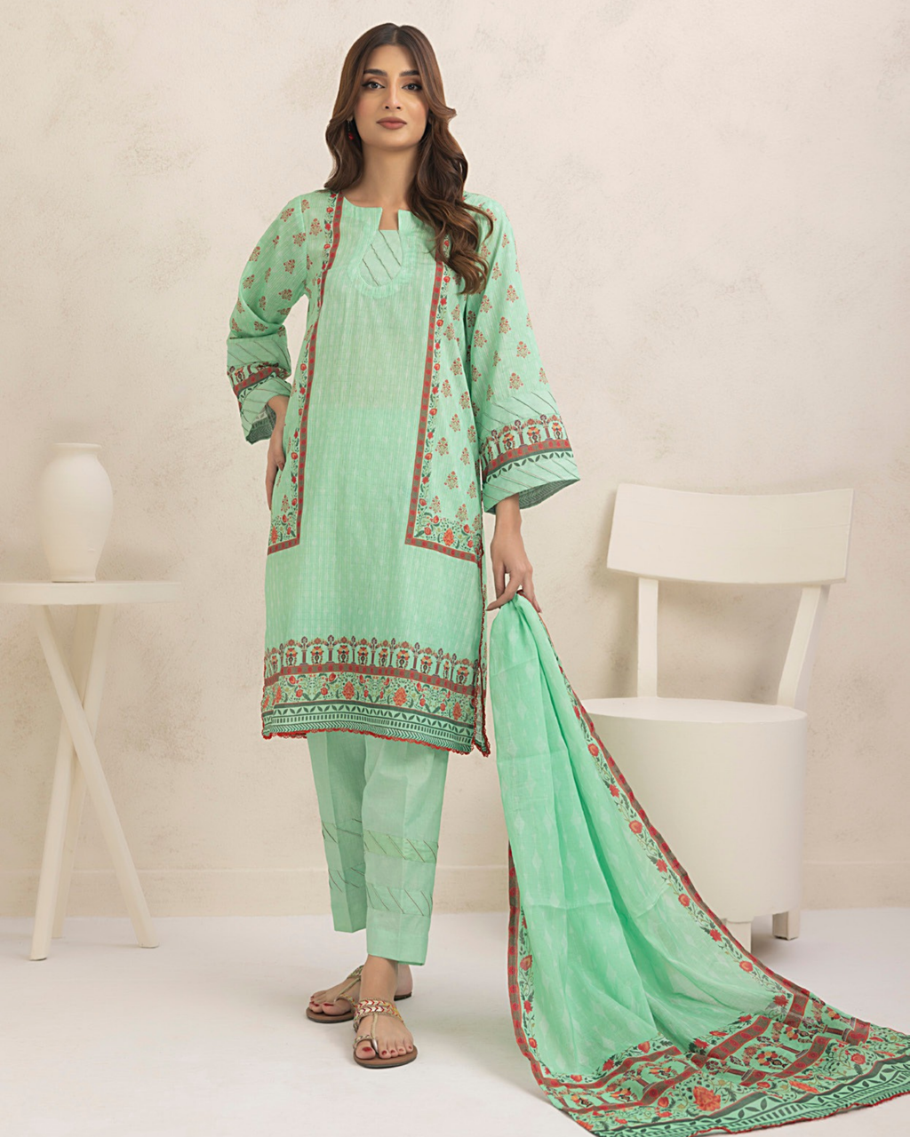 Woman wearing a light green traditional outfit with red patterns on a white background