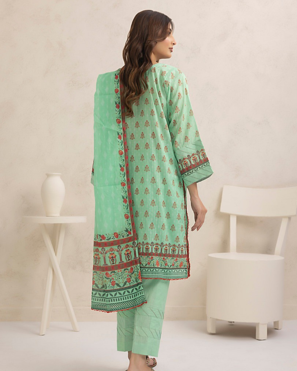 Woman wearing a light green traditional outfit with a matching dupatta in a minimalistic room.