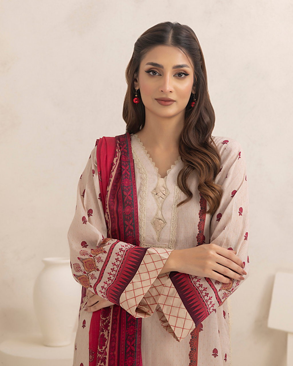 Woman wearing a traditional outfit with a red and beige patterned shawl on a white background