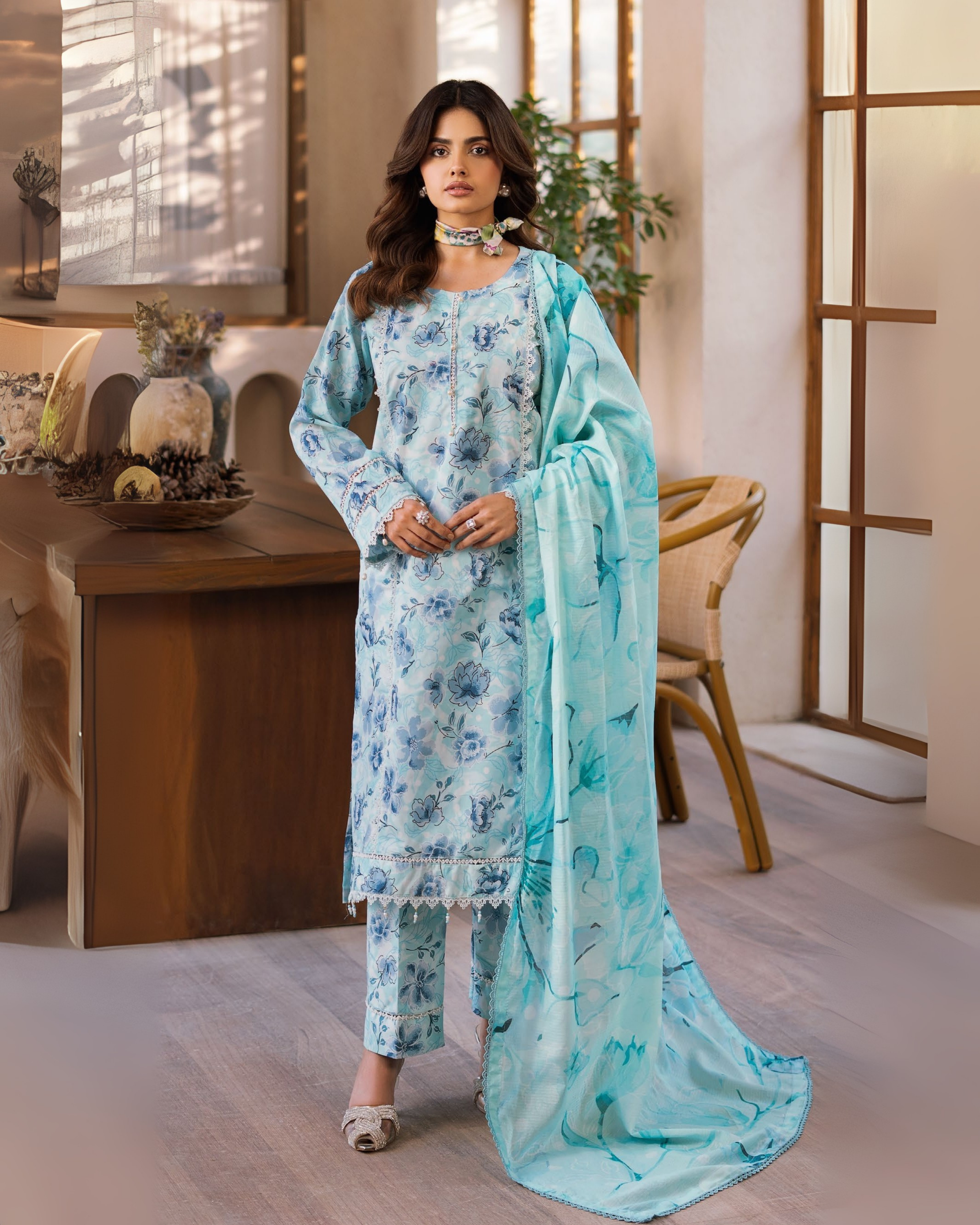 Woman in a light blue floral outfit with a matching dupatta in an indoor setting.