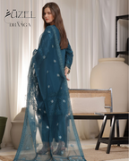Woman wearing a teal traditional outfit with a sheer dupatta in a room setting.