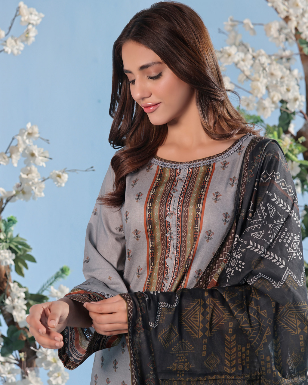 Woman wearing a patterned outfit with cherry blossom trees in the background