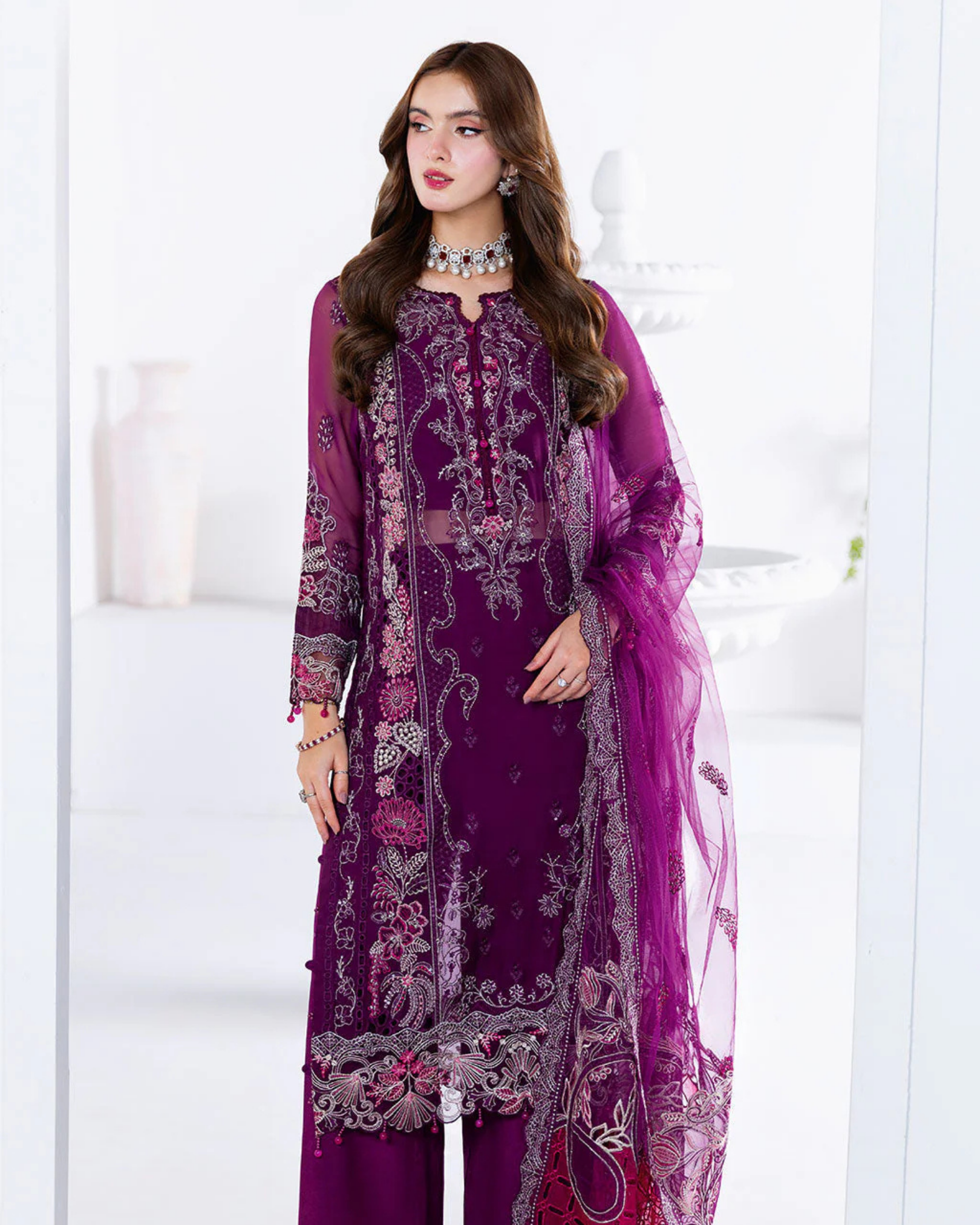 Woman wearing a purple embroidered outfit with a white background