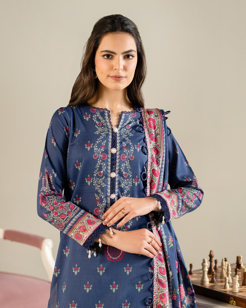 Woman wearing a blue embroidered traditional outfit with a beige background