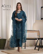 Woman wearing a blue embroidered outfit with a white curtain background