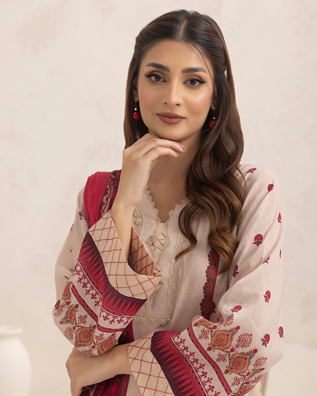 Woman wearing a traditional outfit with red and white patterns on a plain background
