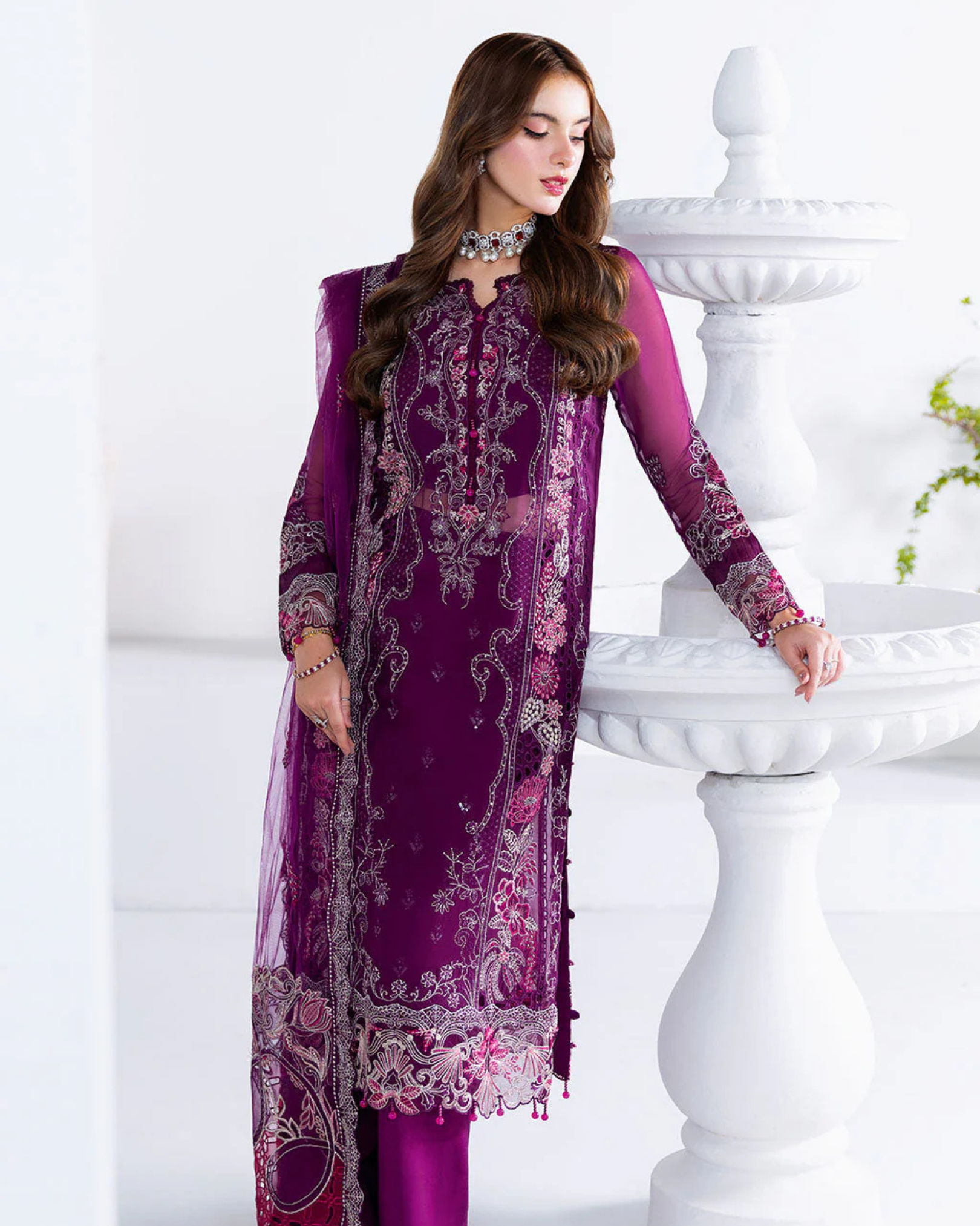 Woman wearing a purple embroidered dress with a white background
