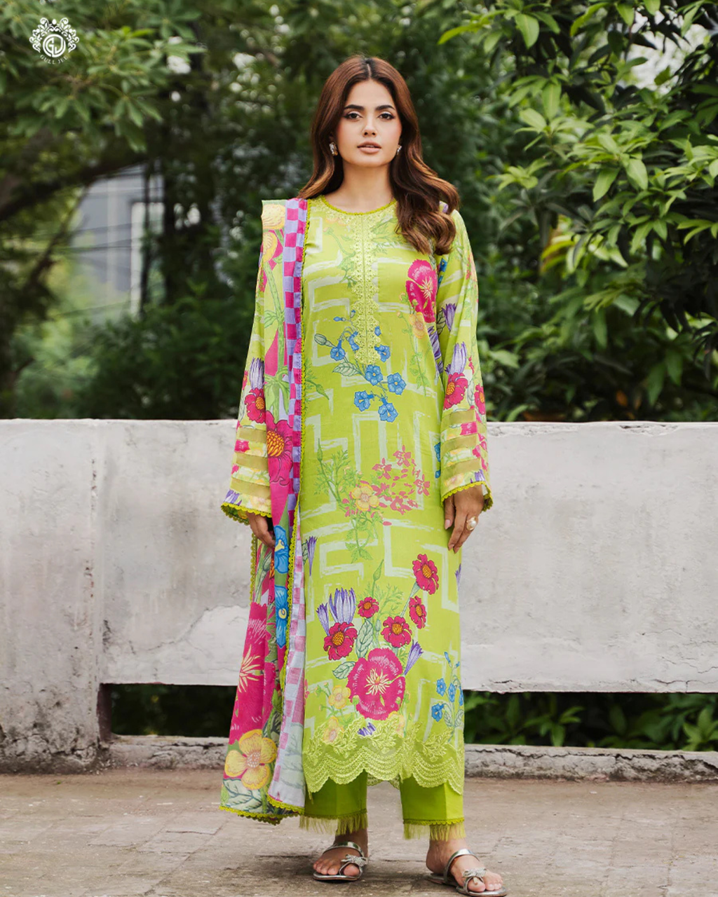 Woman wearing a bright green floral dress with a colorful dupatta against a natural background