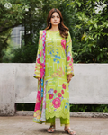 Woman wearing a bright green floral dress with a colorful dupatta against a natural background