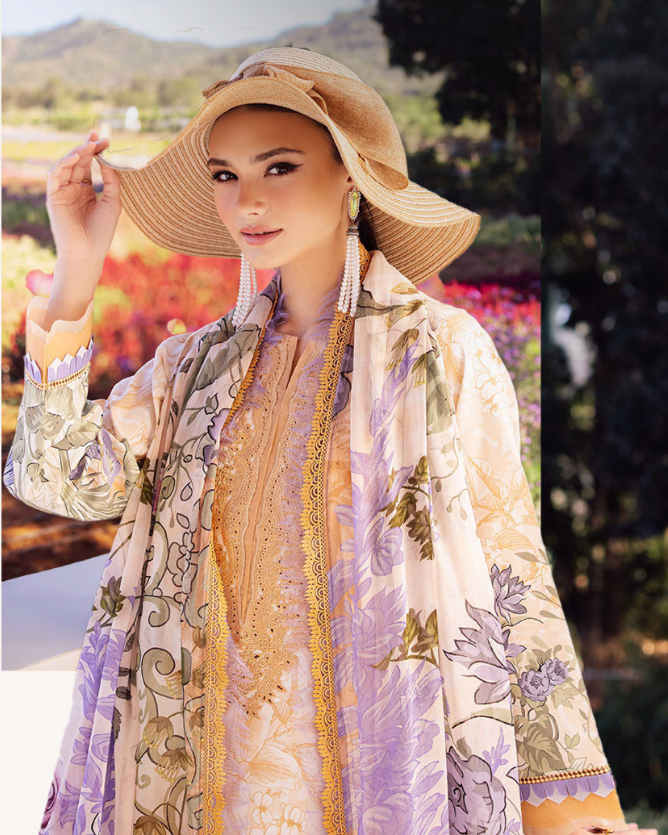 Woman wearing a floral dress and wide-brimmed hat with a scenic background
