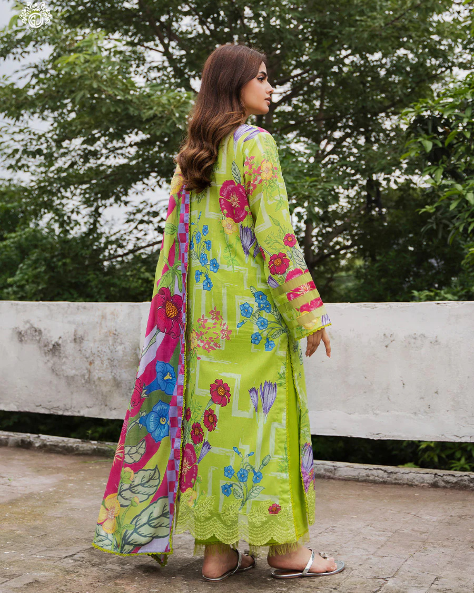 Woman wearing a colorful floral dress with a patterned shawl outdoors.