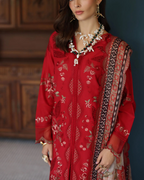 Woman wearing a red embroidered outfit with a patterned scarf against a dark background