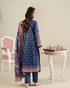 Woman in a blue traditional outfit with floral patterns, standing next to a chessboard.